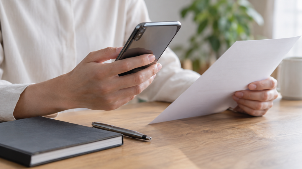 スマートフォンの通知と書類を確認する手元