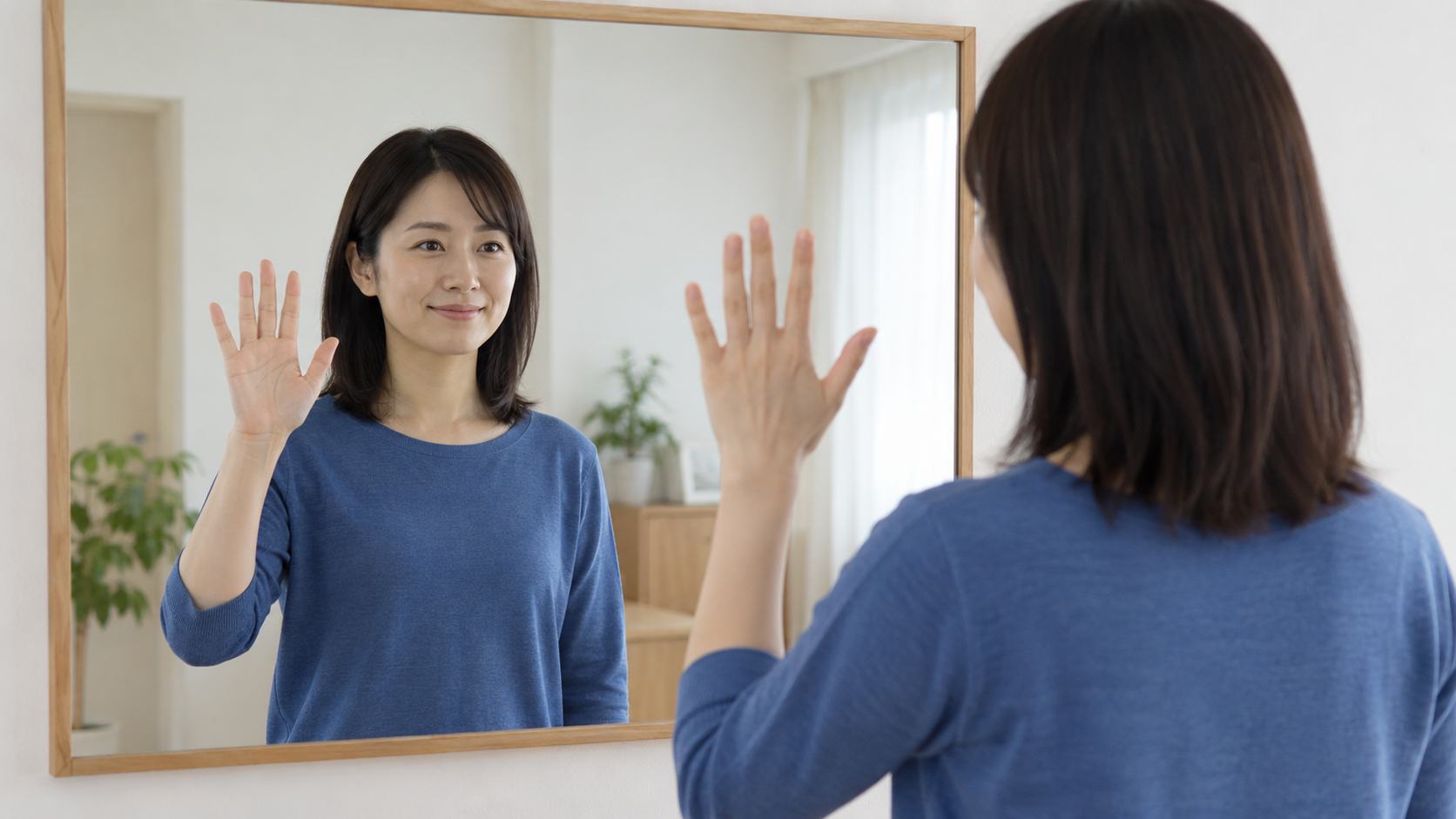鏡の前で片手を上げて映り方を確認する女性