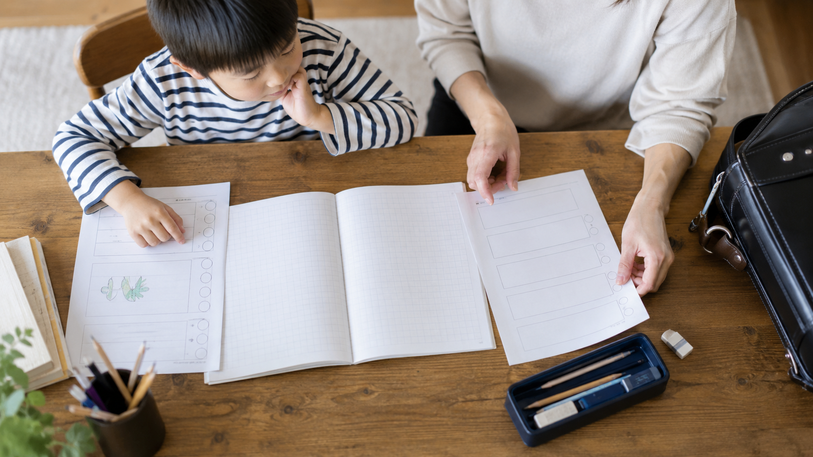 ノートと二枚のプリントを親子で分けて確認する様子