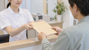 診療記録の入った封筒を受け取る患者